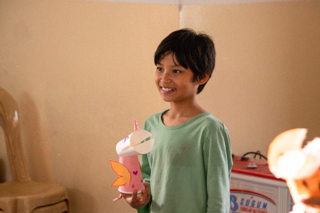 Child holding his unicorn paper craft creation