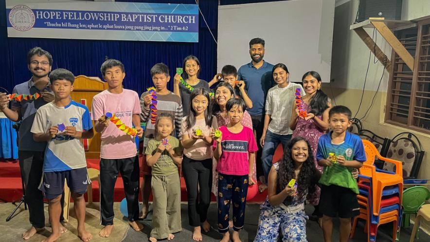 LMl volunteers group photo with children from Lions Hope Home holding their paper springs.