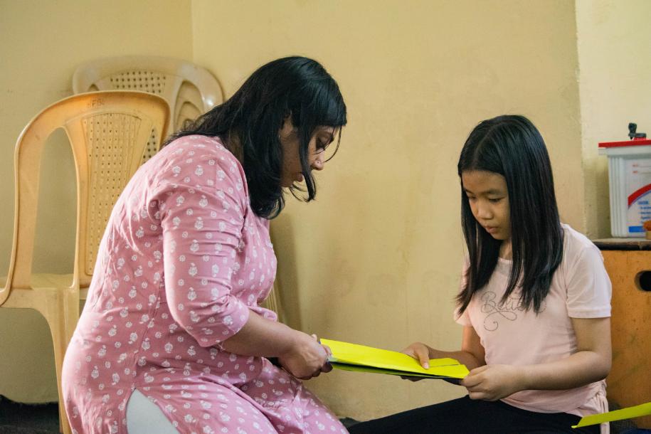 LML volunteer helping child make a paper spring.